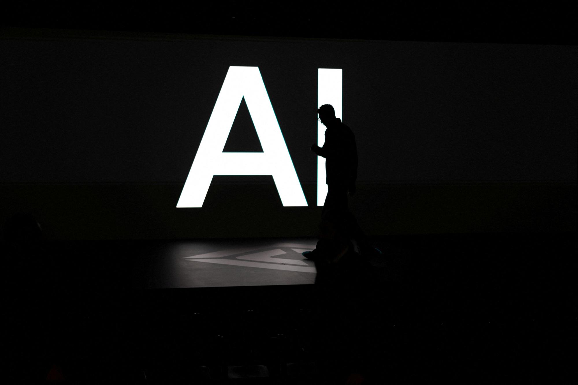 A screen reads 'AI' in reference to artificial intelligence as attendees gather during Rivian's first Autonomy and AI Day, showcasing developments in self-driving technology, in Palo Alto, California, U.S., December 11, 2025. REUTERS/Carlos Barria