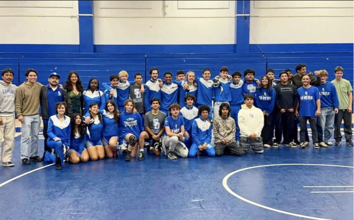 An instagram post from the Cavers wrestling team account on alumni night, December 20, 2025. The photo shows the entire team and coaches. https://www.instagram.com/sdhs.wrestling