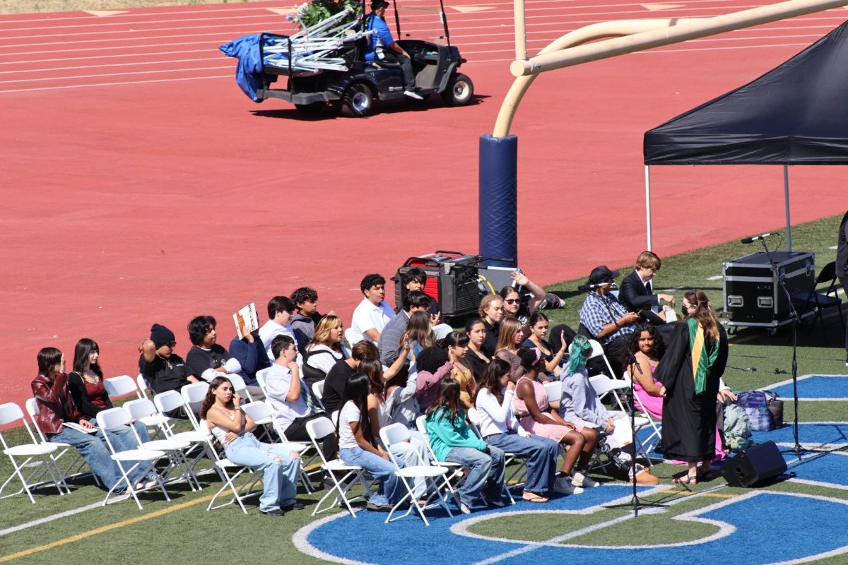 Choir sets up on the field, preparing for the ceremony. They prepare to sing songs like the national anthem and the alma mater